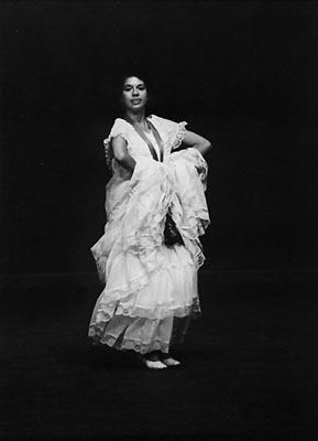 Spanish dancer in lacy white dress on dark stage
